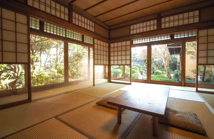 durante o dia, almofadas ao redor de mesa retangular de madeira em suíte de ryokan com vista para árvores