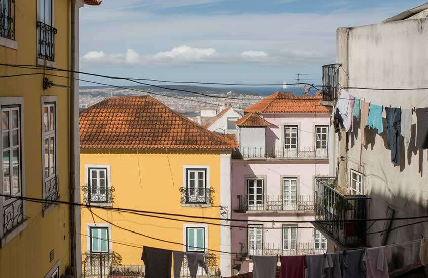 Durante o dia, vista de casas históricas e coloridas em rua de Alfama, bairro para incluir no roteiro lisboa