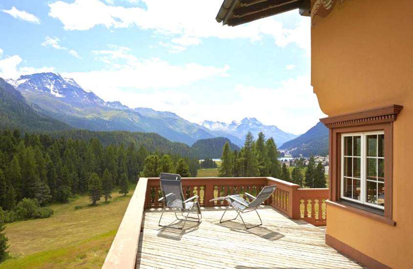 durante o dia, espreguiçadeiras em varanda ao ar livre com vista para árvores e montanhas em hotel onde ficar em St. Moritz