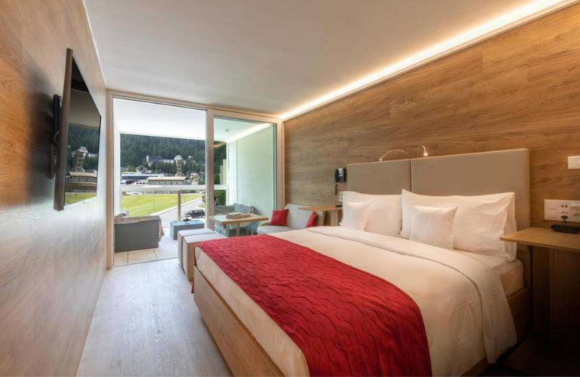 durante o dia, cama de casal e televisão na suíte de um hotel em St. Moritz com vista para a cidade