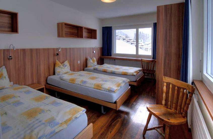 durante o dia, três camas de solteiro e cadeiras de madeira em hotel em St. Moritz com vista para as montanhas