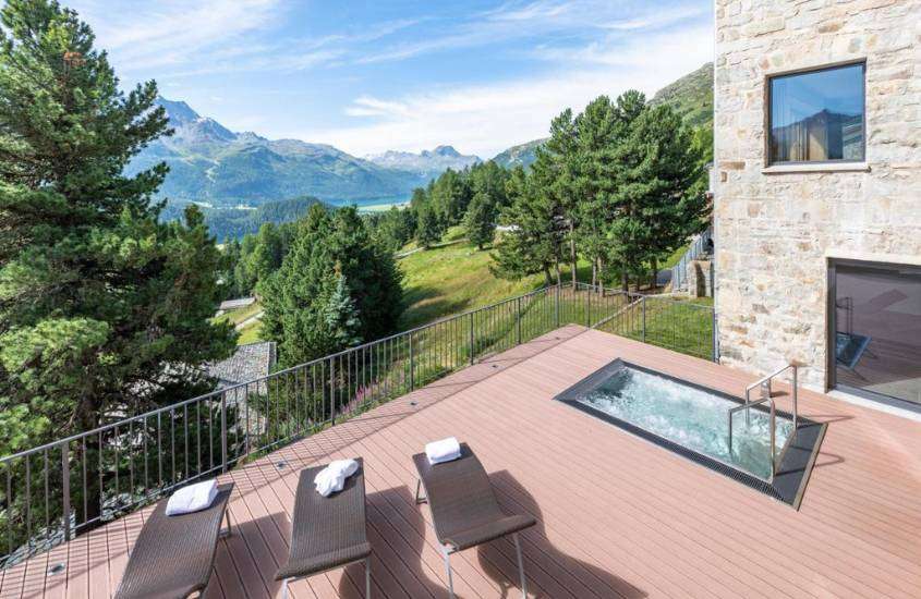 durante dia ensolarado, vista de cima de espreguiçadeiras e pequena piscina em deck de madeira ao ar livre com vista para árvores e montanhas