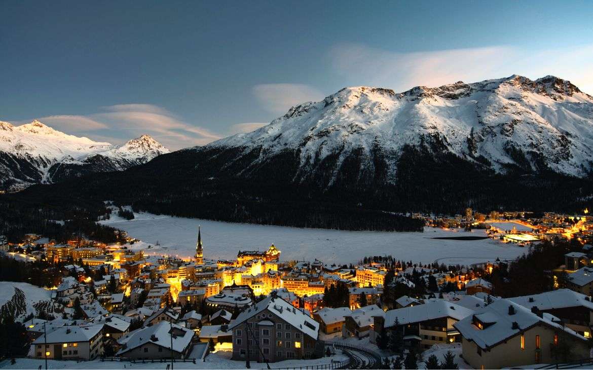 durante anoitecer, vista aérea de casas iluminadas em frente a montanhas cobertas de neve