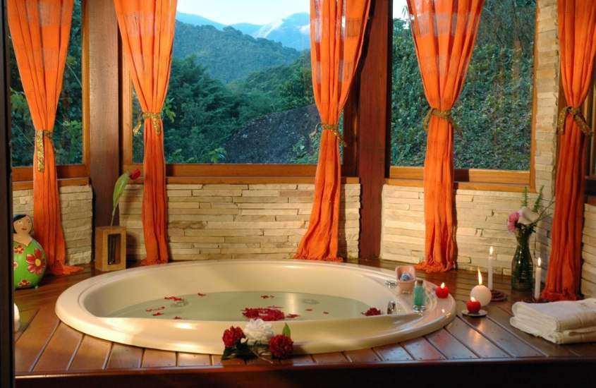 durante o dia, velas e rosas em borda de banheira de hidromassagem redonda em suite com vista para as montanhas