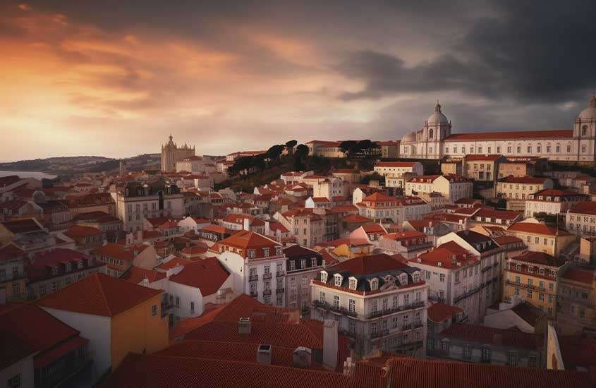 vista aérea e construções e prédios brancos com telhados laranjas, iluminados pela luz do entardecer, em portugal