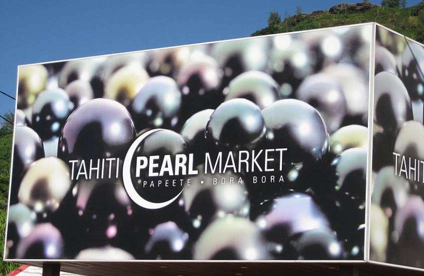 durante o dia, placa com foto de pérolas negras, onde há escrito em branco ''tahiti pearl market, papeete - bora bora''