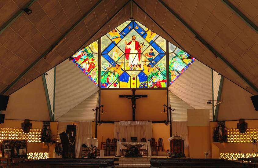 bancos de madeira em frente a altar de igreja, com vitrais coloridos