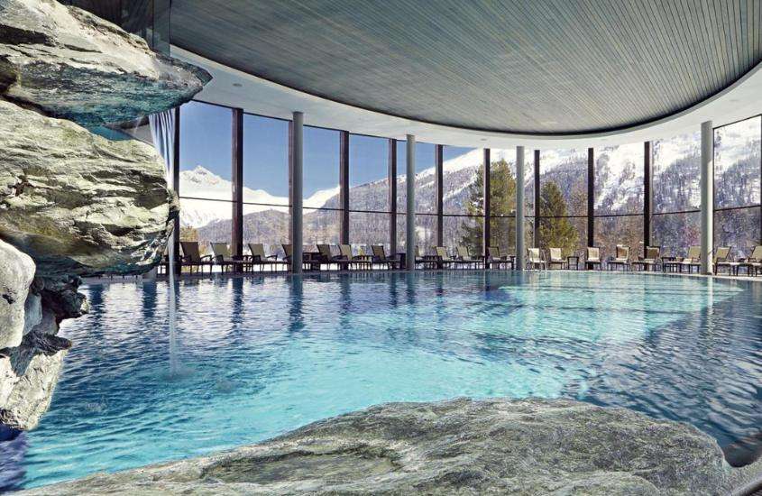 durante o dia, espreguiçadeiras ao redor de grande piscina coberta em SPA com vista para as montanhas