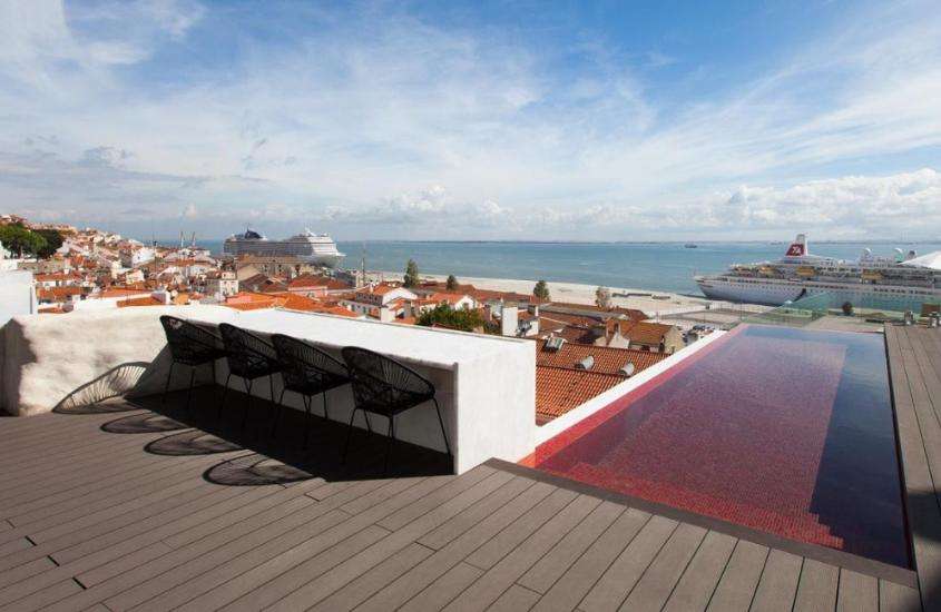 durante dia ensolarado, cadeiras pretas e piscina em cobertura de hotel com vista para o mar