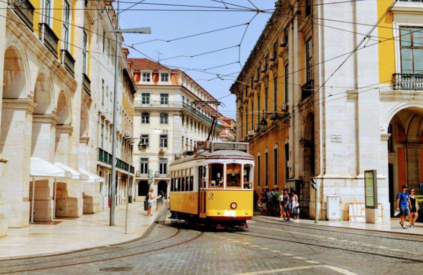 durante o dia, bondinho amarelo passando em rua de chiado, um lugar onde ficar em Lisboa