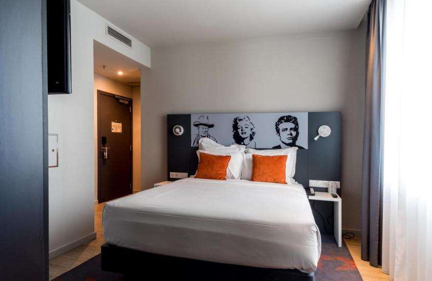 travesseiros brancos e almofadas laranjas em cima de cama de casal em suíte de um dos melhores hotéis em lisboa próximo ao aeroporto
