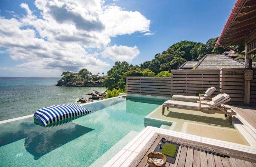 durante o dia, espreguiçadeiras e piscina ao ar livre com vista para o mar em deck de hotel em seychelles