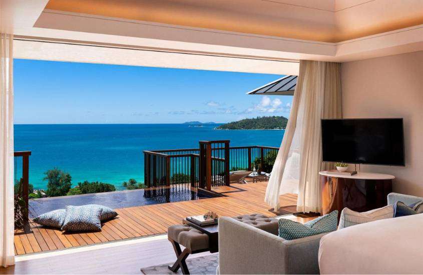 durante o dia, sofá e tv em sala de estar de suíte com varanda e ampla vista para o mar