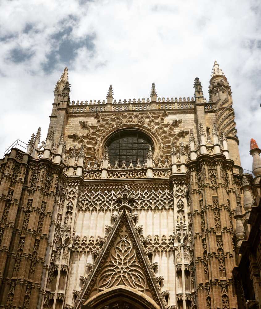 durante o dia, Catedral de Sevilha, com sua arquitetura gótica, vista sob o céu com nuvens brancas