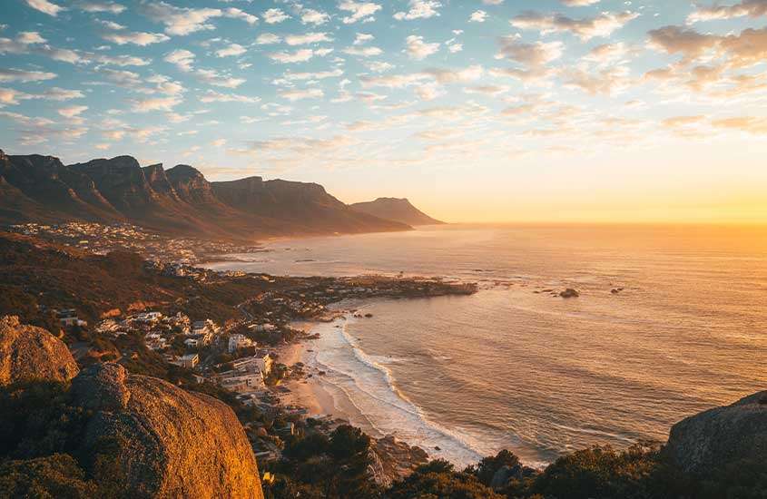 Durante o entardecer, vista aérea de montanhas em frente ao mar na Cidade do Cabo, África do Sul, um dos lugares baratos para fazer intercâmbio