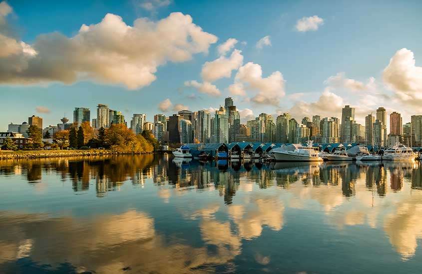 Durante o dia, vista de edifícios modernos à beira do rio em Vancouver, com barcos atracados na água