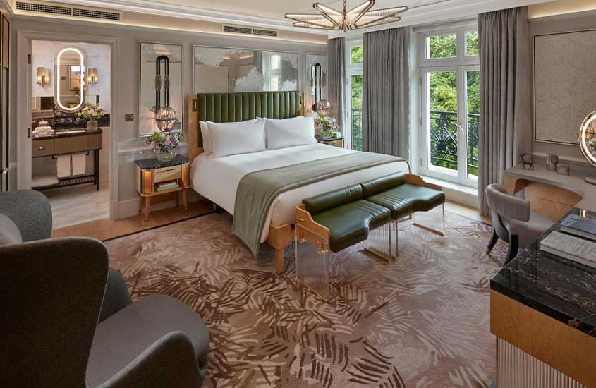 durante o dia, poltronas e cama de casal em suíte de hotel em Londres com vista para jardim.