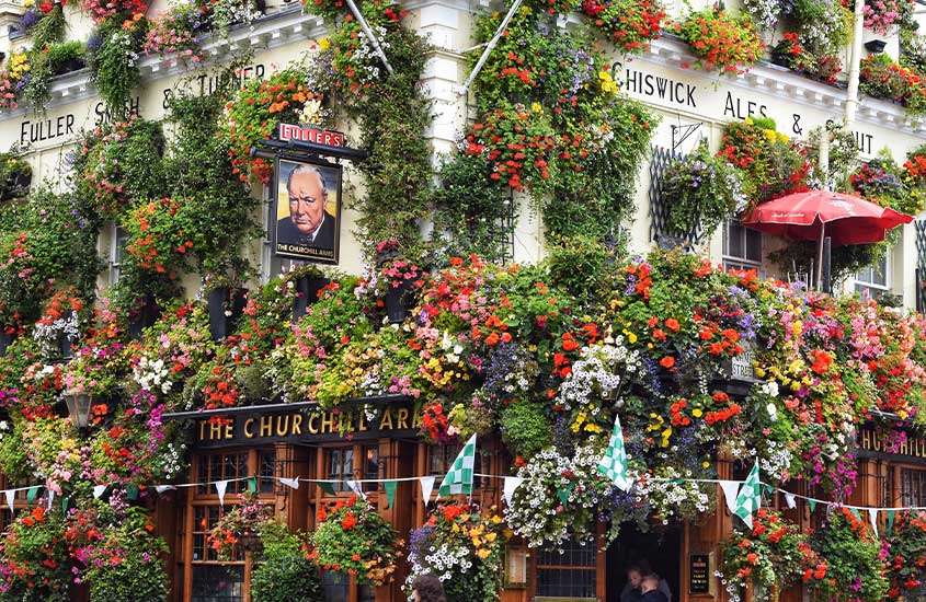 Durante o dia, fachada de loja com parede repleta de flores e plantas em Notting Hill, um dos melhores lugares para ficar em Londres.