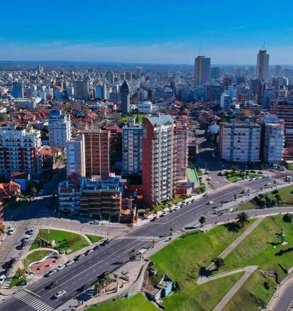 Durante o dia, vista aérea de prédios altos e modernos às margens de avenida movimentada, com carros passando, em Buenos Aires
