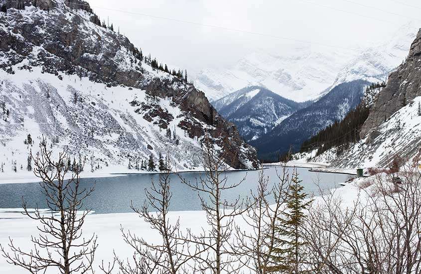 durante dia nublado, montanhas nevadas ao redor de lago em Banff, um dos destinos para esquiar no Canadá