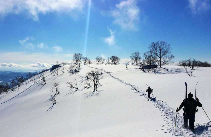 durante o dia, pessoas caminhando em montanha nevada em niseko, no japão