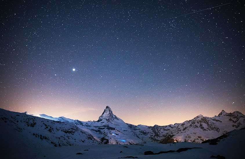 durante a noite, céu estrelado sobre montanhas nevadas em zermatt, um dos melhores lugares para esquiar no mundo