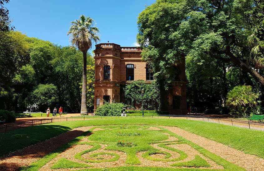 durante dia ensolarado, prédio de tijolos laranjas em meio a árvores verdes em Palermo, um lugar popular onde ficar em Buenos Aires