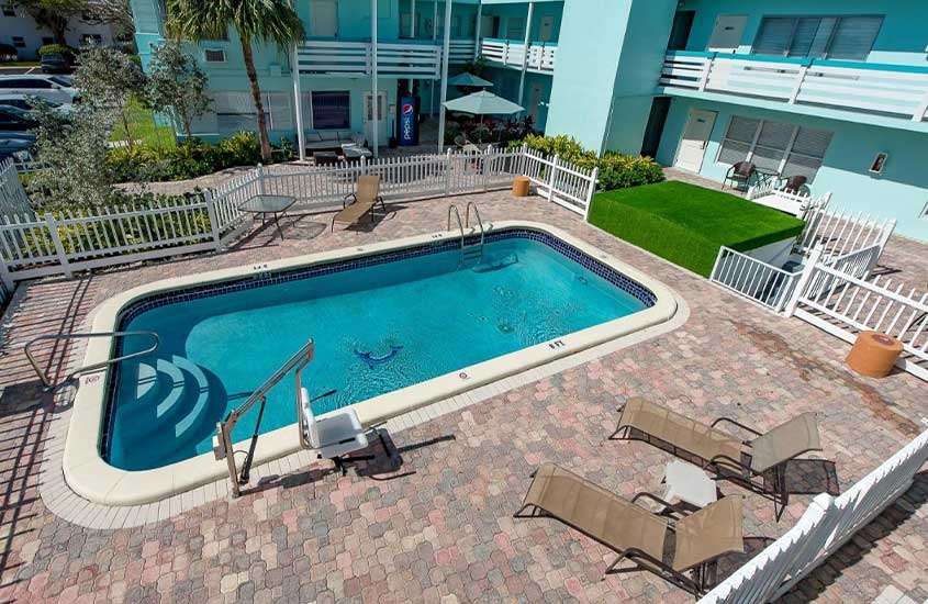 durante um dia ensolarado, espreguiçadeiras ao redor de piscina retangular ao ar livre em área de lazer de um dos hotéis em Fort Lauderdale perto do porto