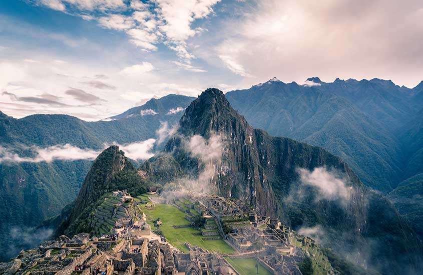Durante o dia, vista aérea de montanhas imponentes no Peru cobertas por nuvens.