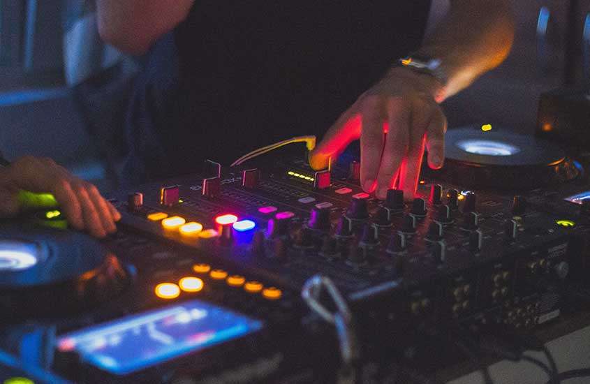 DJ tocando música em uma festa de ano novo em campos do jordão, com suas mãos sobre a mesa de mixagem
