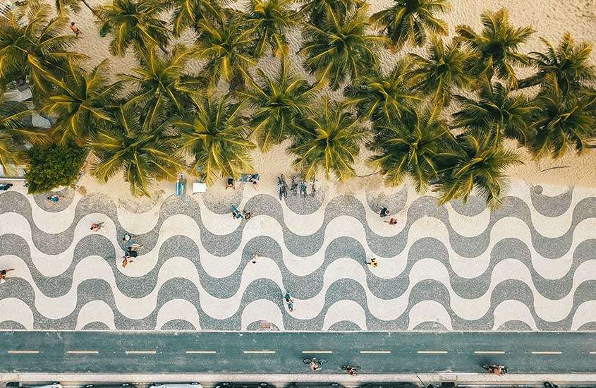 durante o dia, vista aérea de árvores em areia de praia, calçadão e pista de ciclovia em praia de copacabana, um dos para passar o réveillon rio de janeiro 2024.