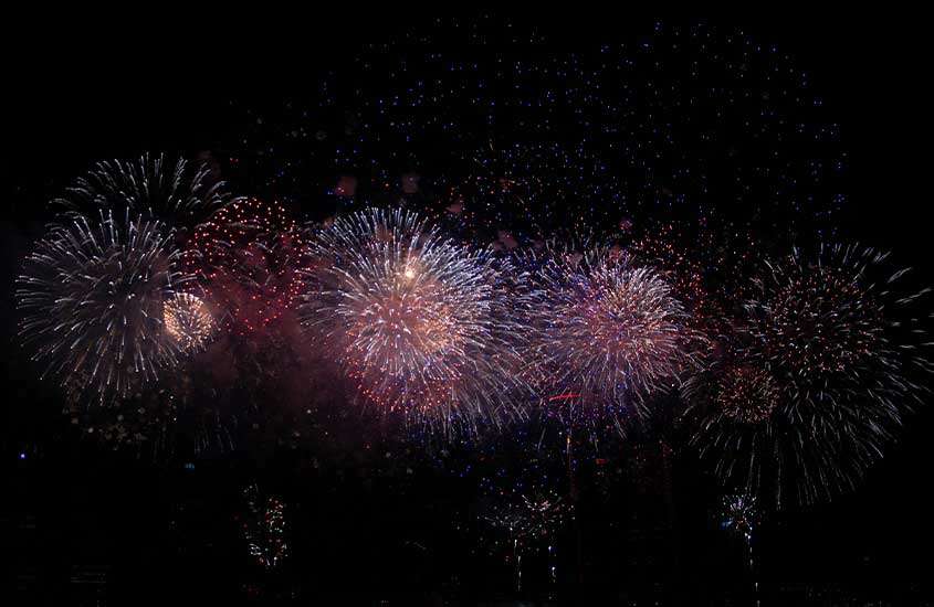 Durante a noite, um espetáculo de fogos de artifício ilumina o céu em uma festa de réveillon em Salvador.
