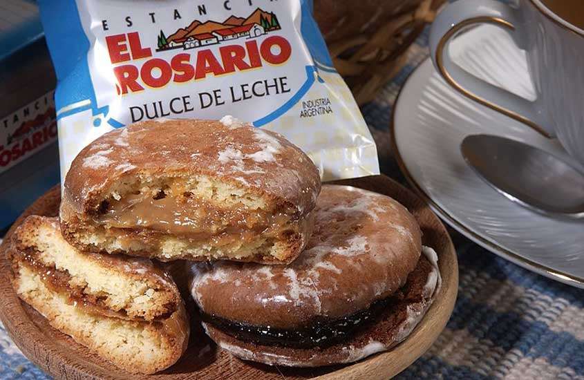 Bandeja de madeira com pedaços de alfajores, um doce tradicional argentino, recheados com doce de leite e cobertos com chocolate, servidos em um local onde comer em bariloche