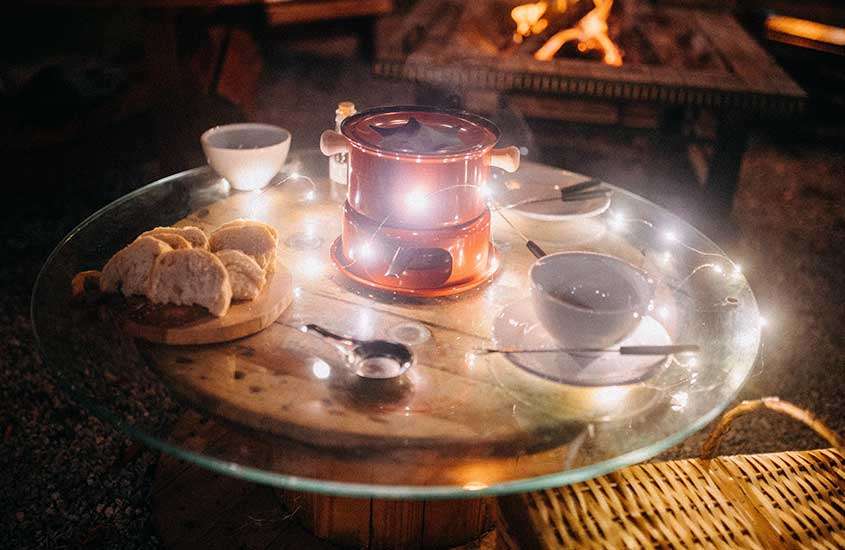 panela com fondue, em cima de mesa de madeira em um restaurante em bariloche