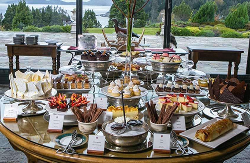 pães, patês, biscoitos, macarons, tortas deoces e salgadinhos servidos em mesa de madeira redonda em um hotel em bariloche