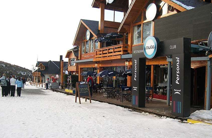 durante o dia, mesas e cadeiras de madeira dispostas ao ar livre em um charmoso restaurante em Bariloche, localizado em uma aconchegante cabana de madeira