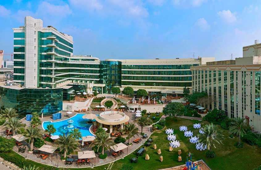 Durante o dia, vista aérea de árvores e piscina em área de lazer ao ar livre em um dos melhores hotéis em dubai próximo ao aeroporto
