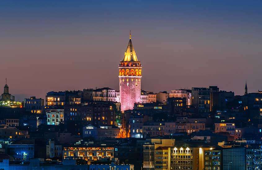 durante a noite, torre de gálata iluminada, rodeada por diversos prédios