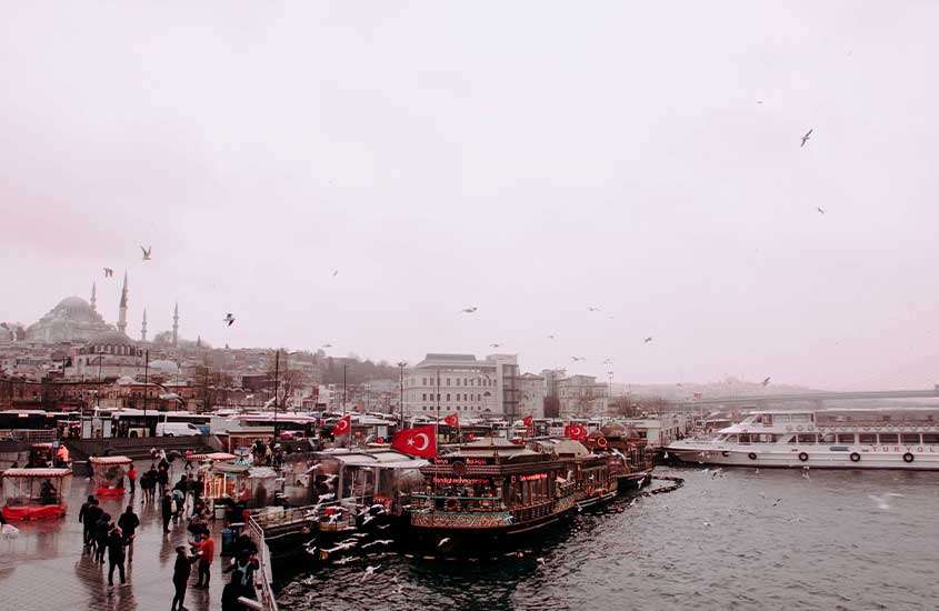 durante um dia nublado, pessoas caminhando em frente a porto em Karakoy, um lugar ode ficar em Istambul
