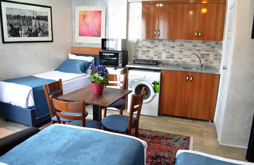 três camas de solteiro, mesa de jantar quadrada, máquina de lavar, armários e cozinha e pia em um dos melhores apartamentos em Istambul