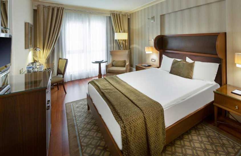 estante de madeira, cama de casal e poltrona em suíte de hotel em Istambul