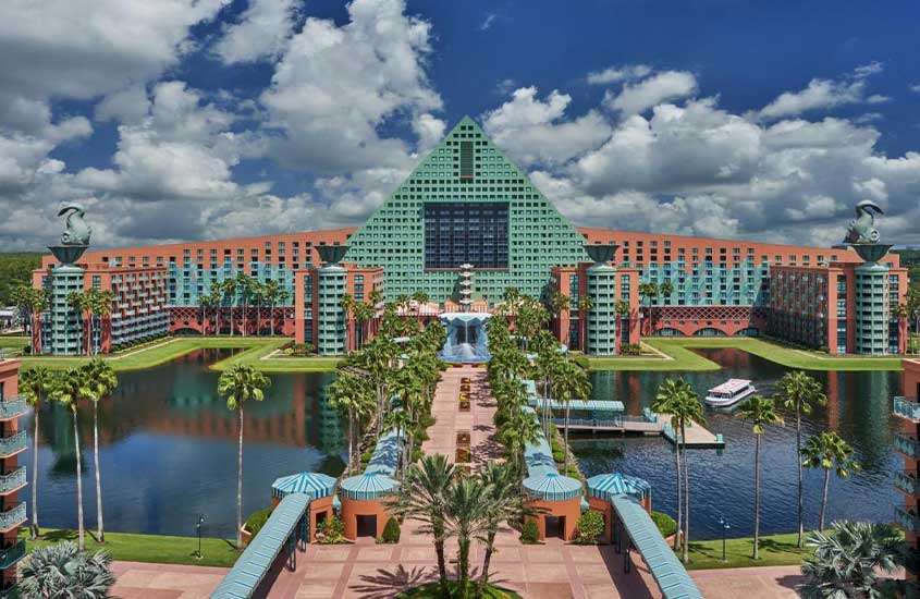 Durante o dia, vista aérea de um amplo complexo com prédios de tons azuis e rosas, situado às margens de um rio no complexo Disney, o melhor lugar para ficar em Orlando próximo aos parques
