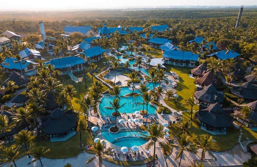 durante um dia ensolarado, vista aérea de diversas piscinas rodeadas por árvores em complexo de um dos melhores resorts em porto de galinhas