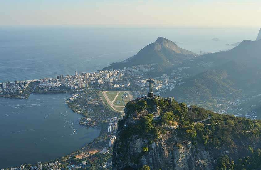 Durante o dia, vista aérea do Cristo Redentor no topo de montanha, montanhas, mar e prédios no Rio de Janeiro