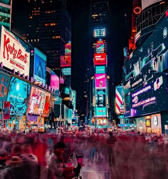 Multidão animada reunida na Times Square durante a festa de Réveillon em Nova York, com as luzes e letreiros brilhantes ao fundo.