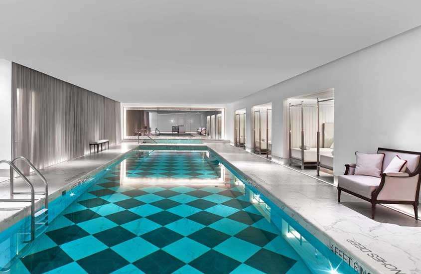 poltronas em frente a grande piscina retangular em área de lazer coberta de um dos hotéis em nova york