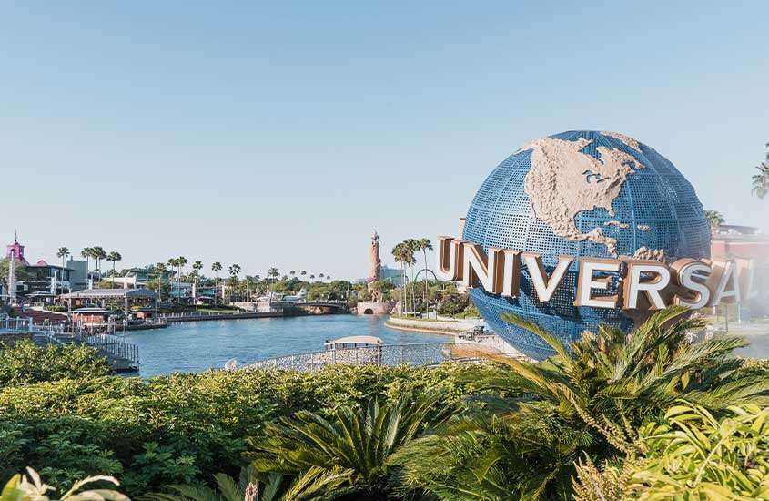 Entrada ensolarada do parque temático Universal Studios em Orlando, com um grande globo decorativo em destaque.
