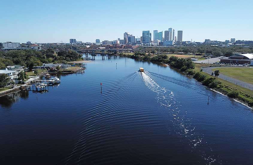 vista aérea, durante um dia ensolarado, de barco passando em rio em tampa, uma das principais cidades da flórida.