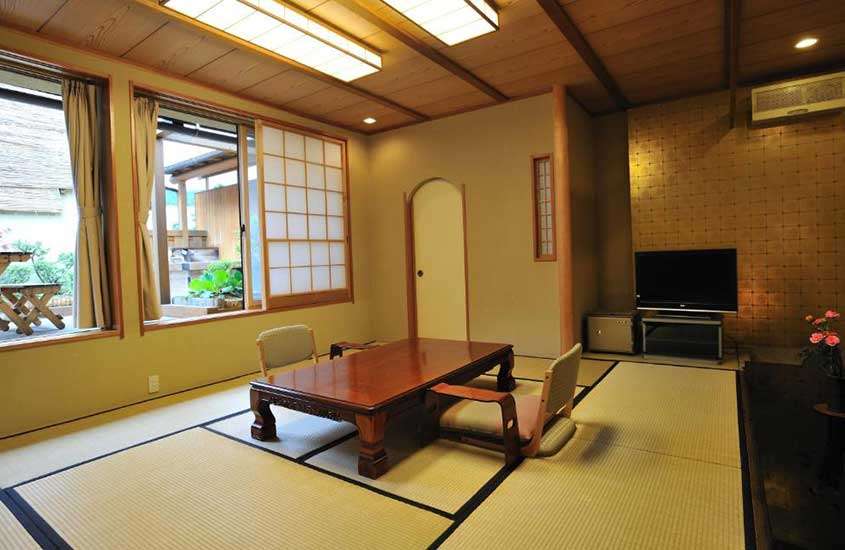 Cadeiras e mesas em estilo japonês, com design minimalista e baixas ao chão, dispostas em uma suíte de ryokan em Nagano.