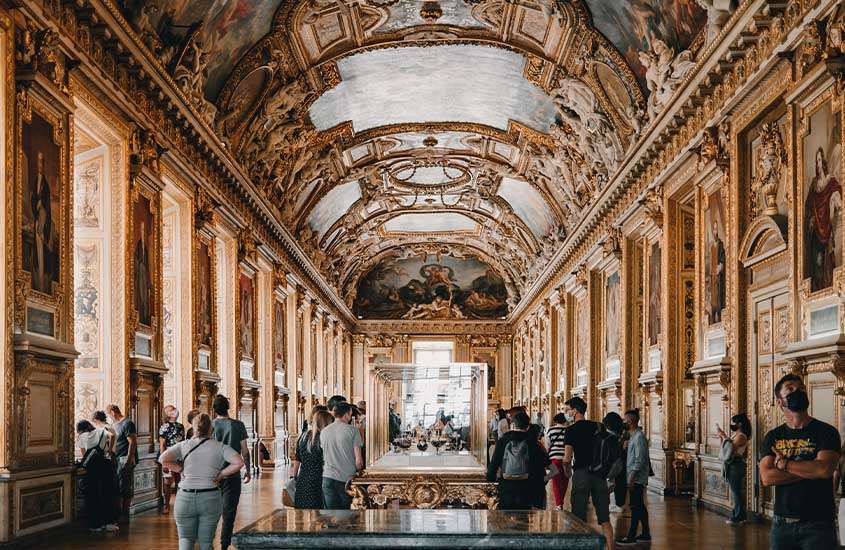 pessoas observando obras de arte em exposição no Louvre